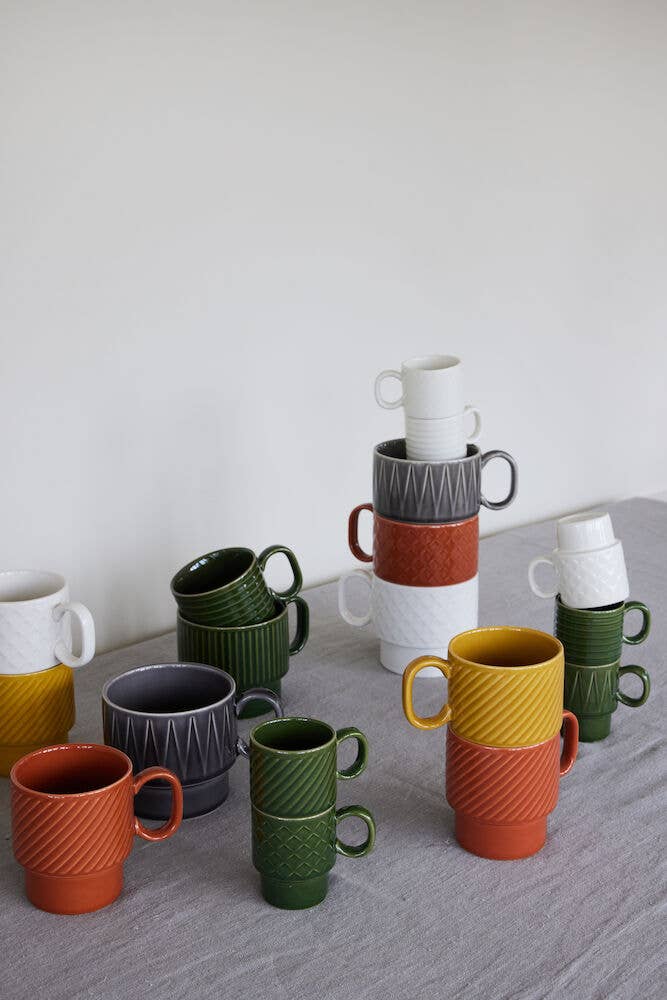 Die farbenfrohen Becher der Sagaform GmbH Coffee & More Teetasse in den Farben Weiß, Grau, Grün, Gelb und Orange sind auf einem hellgrauen Stoff mit weißem Hintergrund gestapelt - ideal, um Ihre Lieblingsheißgetränke zu genießen. Das Set besteht aus 2 Bechern.