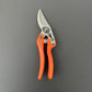 Ein geschlossenes Paar Löwe Original Löwe 11 – Classic Power Cut Gartenschere mit orangefarbenen Griffen und einer silbernen Klinge, abgebildet auf dunklem Hintergrund – perfekt für präziseren Schnitt.
