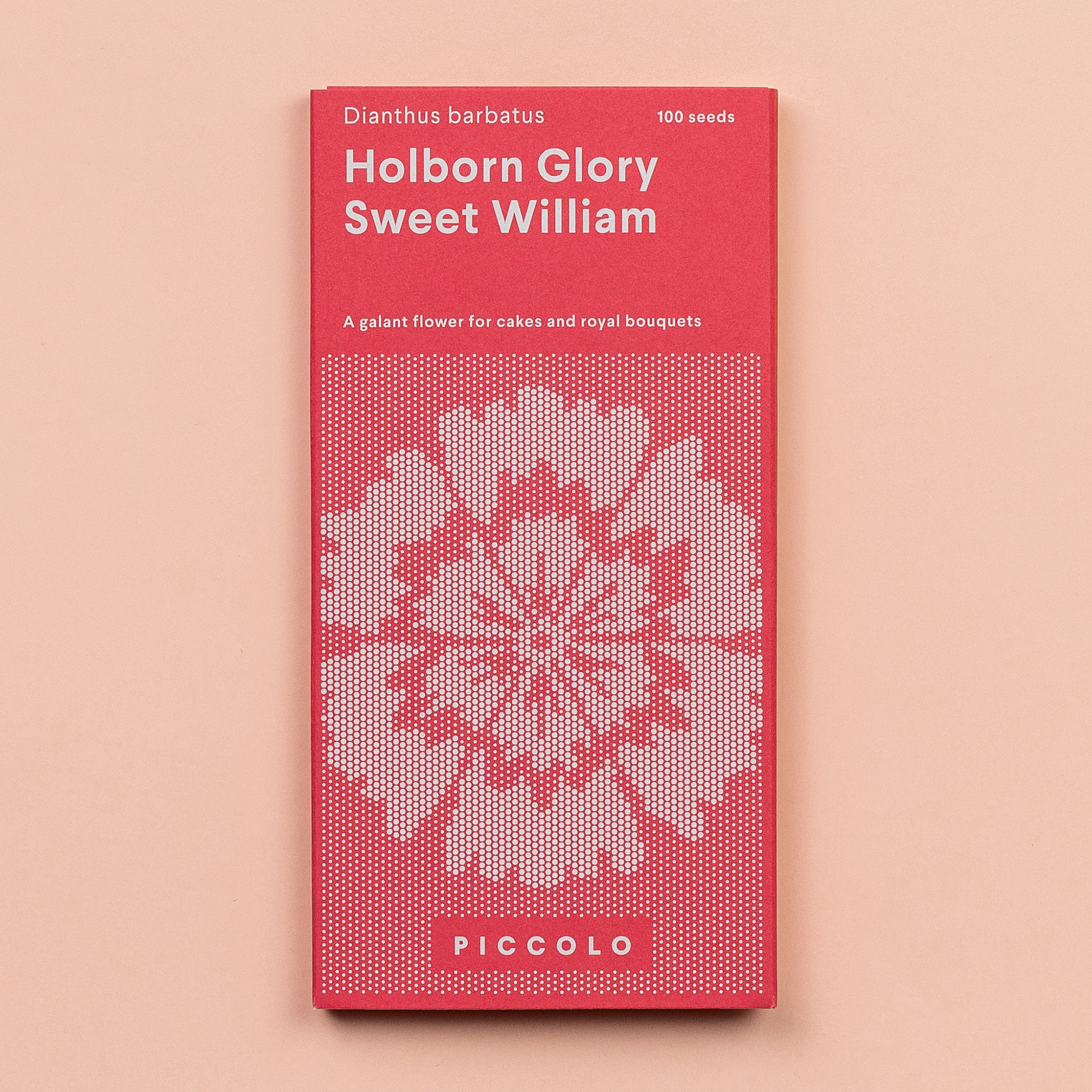 Eine rot-rosa Saatgutpackung mit der Aufschrift Piccolo Seeds - Der süße William Holborn Glory zeigt ein geometrisches Blumenmuster, Dianthus barbatus, essbare Blütenblätter, 100 Samen und die Marke Piccolo Seeds auf einem hellen pfirsichfarbenen Hintergrund.