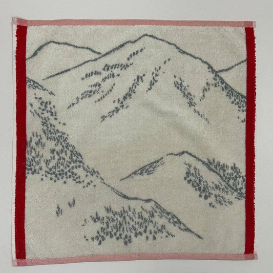 Das Küchenhandtuch "Grandeur nature" von Sylvie Thiriez ist ein weißes Baumwollhandtuch mit roter Bordüre und einem grauen, skizzenhaften Berg- und Baummotiv.