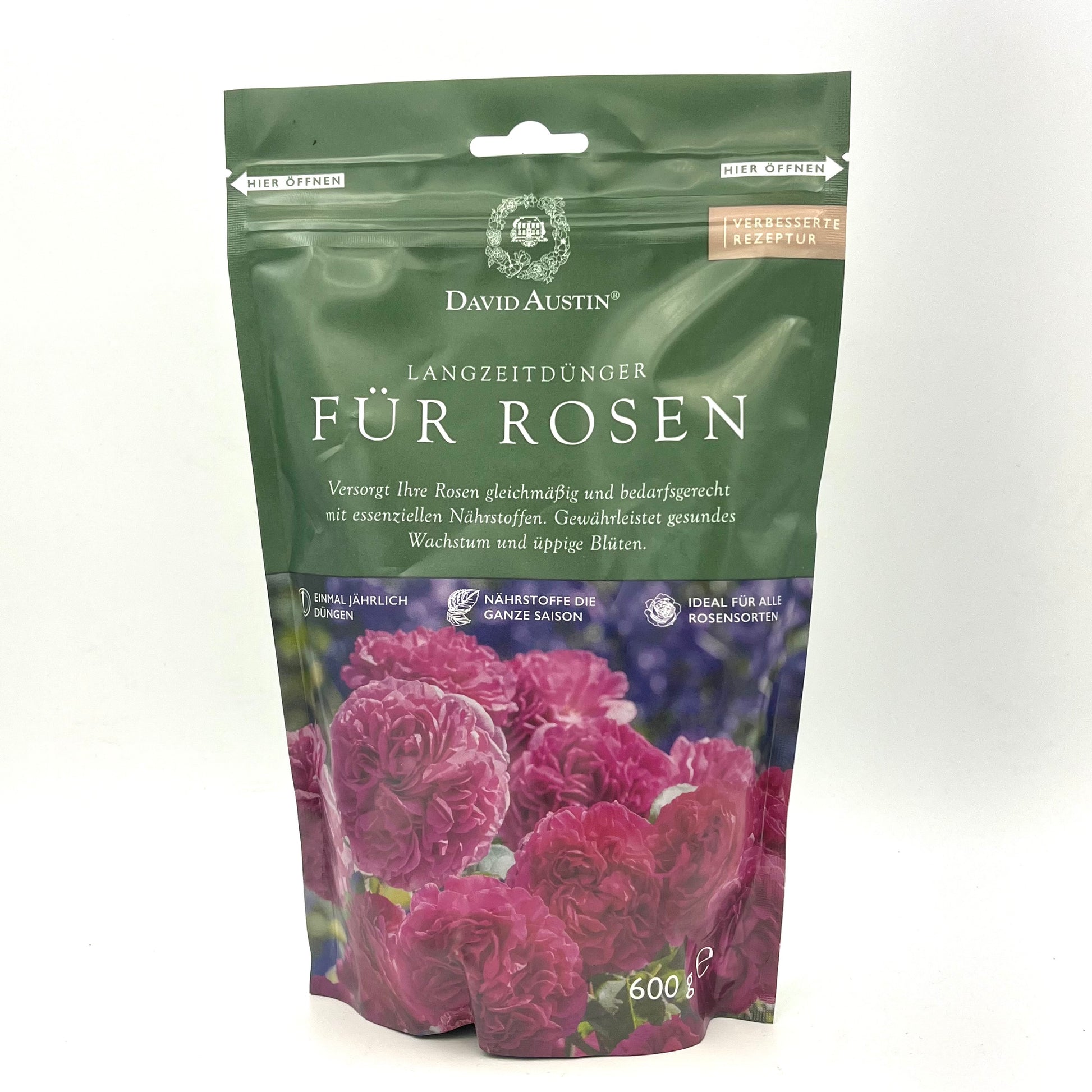 Ein 600g-Beutel David Austin - Langzeitdünger für Rosen besticht durch seine grüne Verpackung mit rosa Rosen und deutschem Text, der für eine gesunde Wurzelentwicklung und lebendige Rosenblüten wirbt.