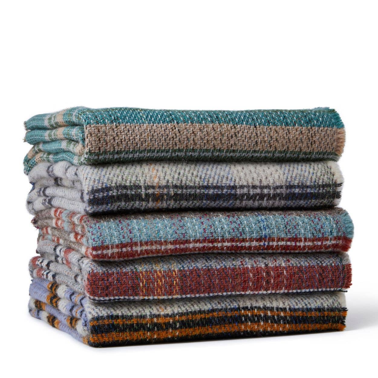 Ein ordentlich gestapelter Stapel von fünf Tweedmill | Zufällige recycelte Wolldecke - Groß - verschiedene Farben von Tweedmill Textiles, mit mehrfarbigen Karomustern im klassischen britischen Stil auf weißem Hintergrund.