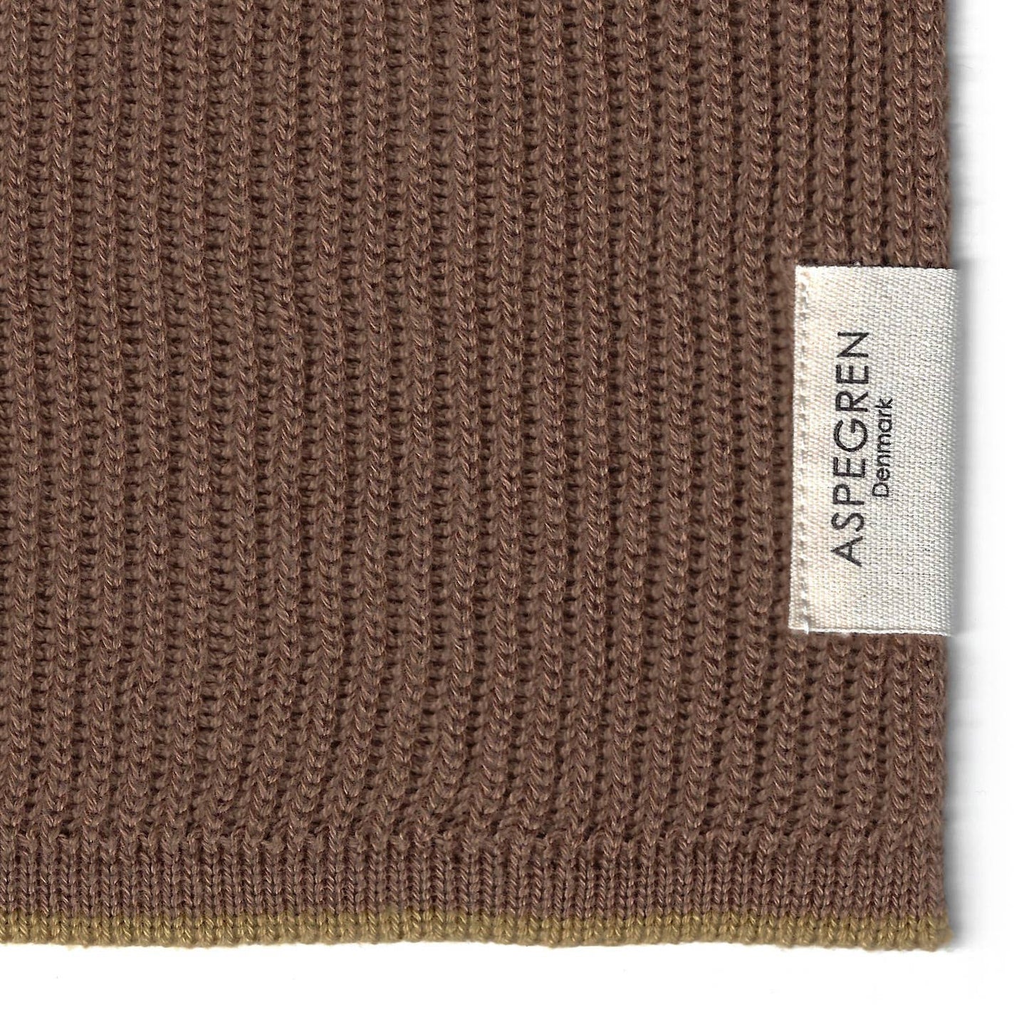 Nahaufnahme eines braunen Rippenstrickstoffs mit weißem Aspegren Denmark"-Label - ideal als umweltfreundliche Küchenhandtücher oder Geschirrtücher im Aspegren Denmark - Geschenkset - Praliné.