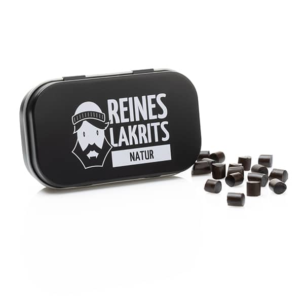 Eine schwarze Metalldose mit der Aufschrift „LASSE LAKRITS – natürlich lecker Dose Reines Lakritz Natur“ und der Grafik eines bärtigen Gesichts ist leicht geöffnet und enthält kleine Stücke von natürlichem Lakritz und Süßholzwurzel, die auf einem weißen Hintergrund verstreut sind.