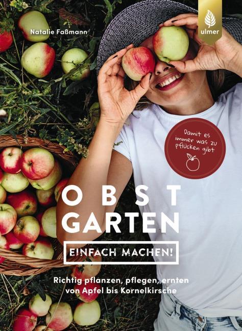Eine Frau liegt lächelnd mit Äpfeln im Gras, umgeben von Körben. Das Buch „Obstgarten – einfach machen!“ aus dem Verlag Eugen Ulmer zeigt spielerisch gestaltete Anleitungen zum Obstanbau – ein frischer Ratgeber für den Garten.