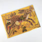Die Hasen Collage Karte von Mark Hearld by Art Angels zeigt einen braunen Hasen, der durch goldgelbes Laub, Brombeeren, Beeren und Blätter springt. Die Signatur des Künstlers erscheint in der Ecke dieser charmanten Leporello-Grußkarte.