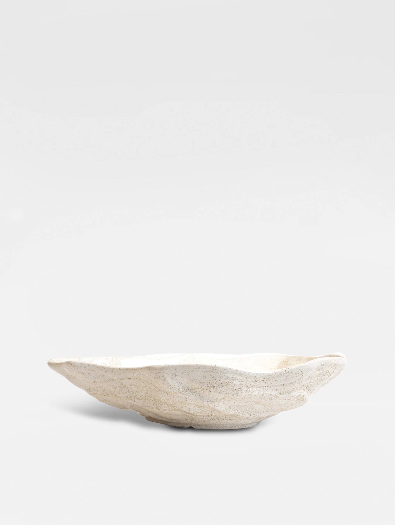 Die BYON Design Schale Alima der Sagaform GmbH ist eine flache, ovale Schale aus New Bone China in natürlichem Beige mit unregelmäßiger Textur und cremefarbenem Farbton auf hellgrauem Hintergrund. Spülmaschinenfest für einfache Reinigung.