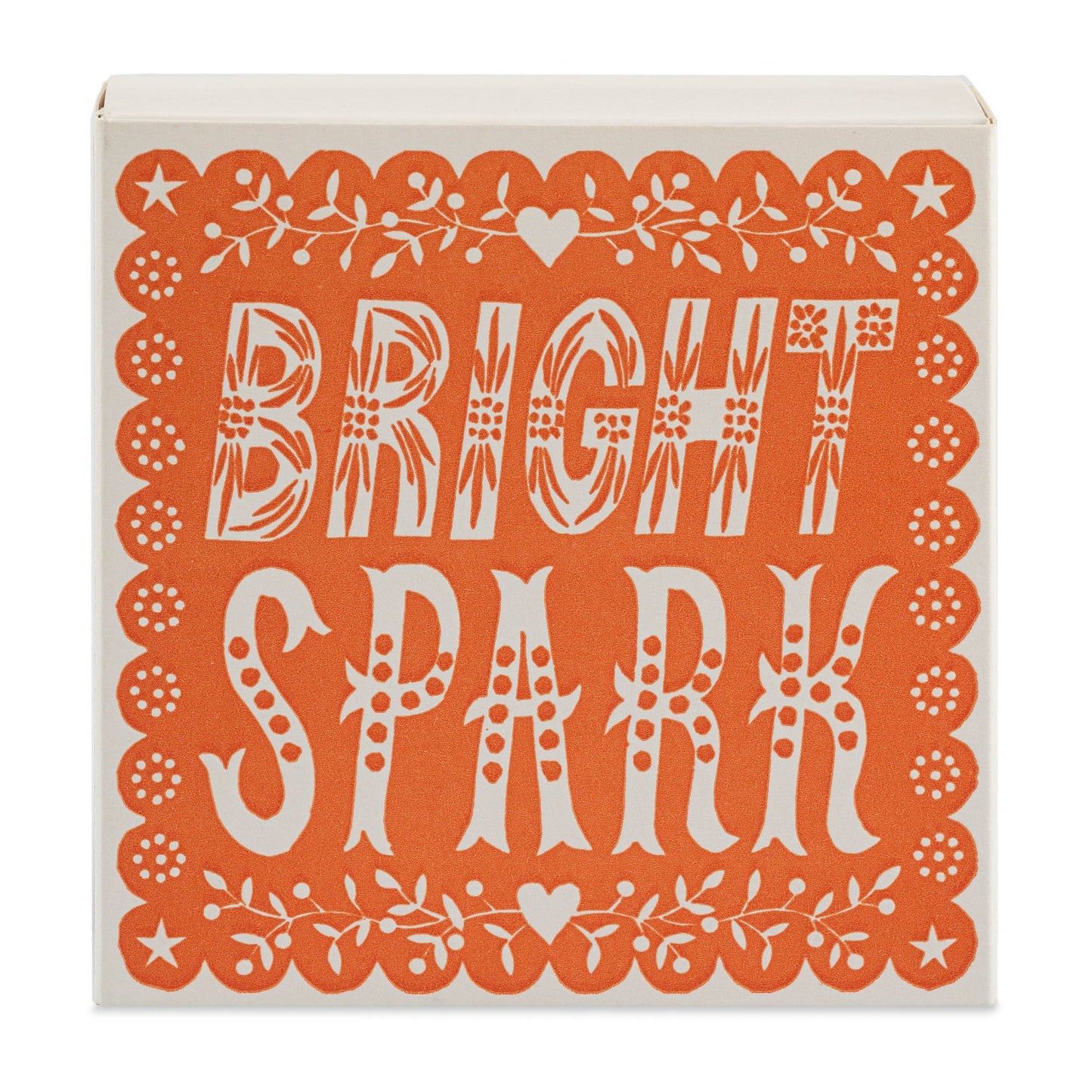 Die quadratischen Streichholzschachteln der Archivist Gallery "Bright Spark" zeichnen sich durch ein orange-weißes Design mit kühnen, gemusterten Schriftzügen und einer geschwungenen Umrandung aus Herzen und Blumen aus, inspiriert von der Linolschnitt-Kunst.