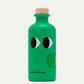Die grüne Flasche mit Holzkappe ist mit Cartoon-Augen und dem Schriftzug "yiayia and friends" am Boden versehen. Auf dem runden Frontetikett steht "Basilikum 200 ml", für yiayia and friends - Natives Olivenöl extra mit Basilikum.