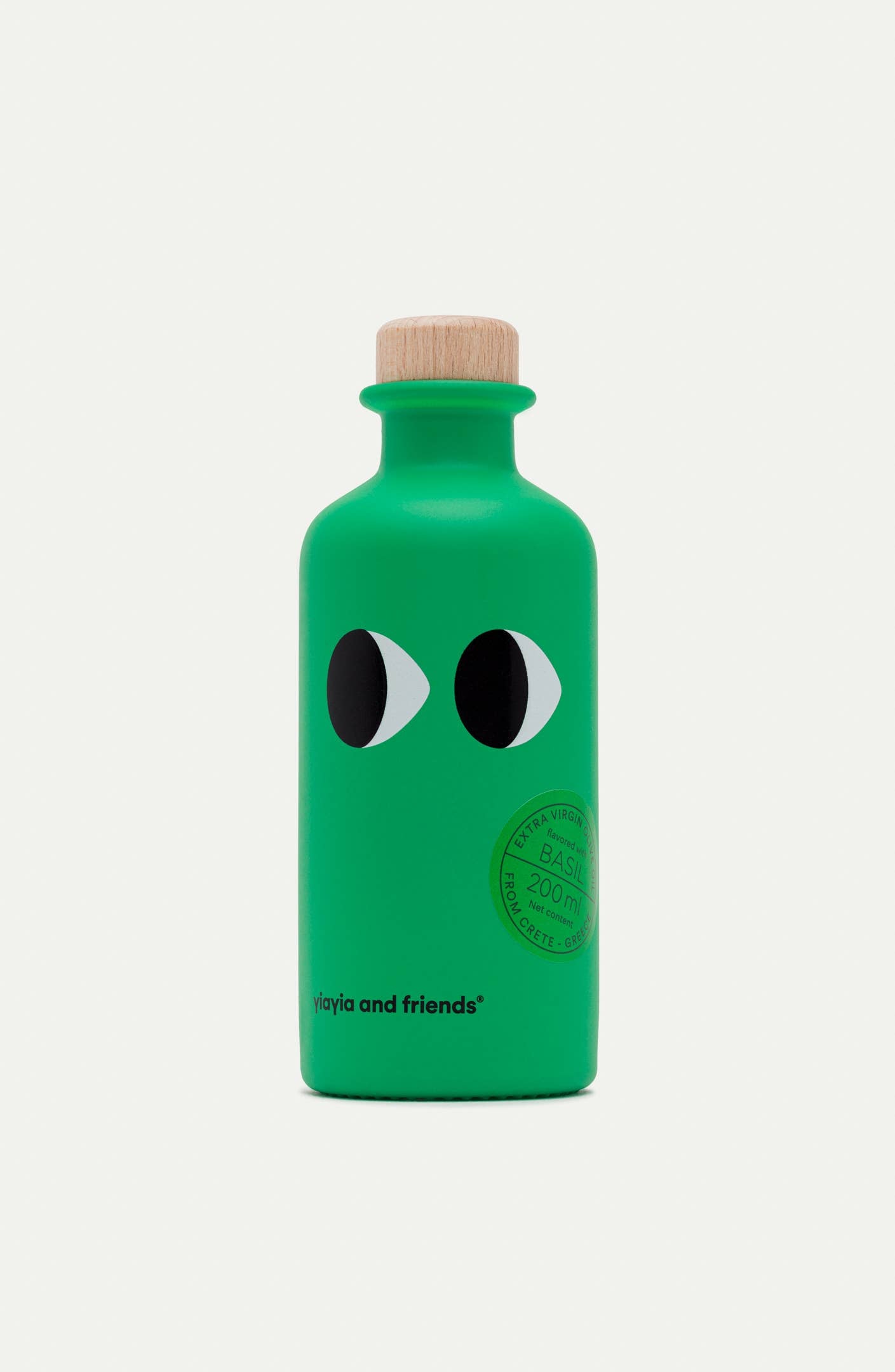 Die grüne Flasche mit Holzkappe ist mit Cartoon-Augen und dem Schriftzug "yiayia and friends" am Boden versehen. Auf dem runden Frontetikett steht "Basilikum 200 ml", für yiayia and friends - Natives Olivenöl extra mit Basilikum.