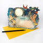 Die Fuchs Collage Karte von Mark Hearld by Art Angels ist eine lebendige Pop-up Karte mit illustrierten Vögeln, einem Kaninchen, Pflanzen und einem leuchtenden Mond, die auf einem gelben Umschlag mit Platz für Ihre Botschaft abgebildet ist.