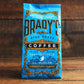 Eine blaue Tüte Brady's Coffee Company - Brady's Signature Blend Kaffee ist mit auffälligen goldenen und schwarzen Details versehen, die die hochwertige irische Röstung hervorheben, die von Brady's Coffee Company in der Grafschaft Wicklow vor einem hölzernen Hintergrund handgefertigt wird.