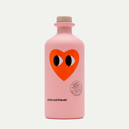 Die pinkfarbene 500-ml-Flasche Natives Olivenöl - Love Edition von yiayia and friends mit Holzkappe zeigt ein großes rotes Herz mit Cartoon-Augen und "Organic Extract 500 mg". Limitierte Auflage - perfekt für Salate.