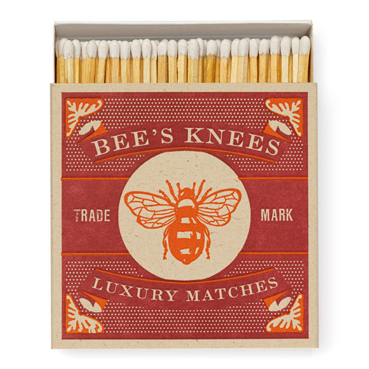 Die Archivist Gallery - Bee's Knees | Square - Sicherheitsstreichhölzer von Archivist Gallery besteht aus einer rot-beigen Schachtel mit einem großen Bienendesign. Im Inneren der geöffneten Schachtel befinden sich Luxus-Streichhölzer aus Holz.