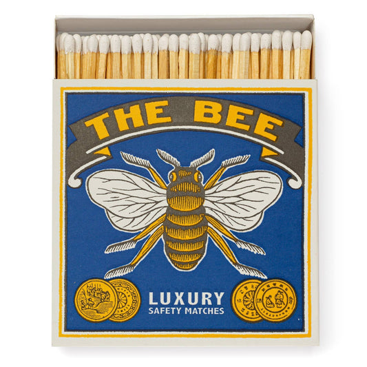 Eine Quadrat-Streichholzschachtel von Archivist Gallery: THE BEE zeigt eine Biene, zwei Goldmünzen und "Luxury Safety Matches" auf blau-gelbem Design. Der Klassiker wird geöffnet präsentiert, sodass die Streichhölzer sichtbar sind.