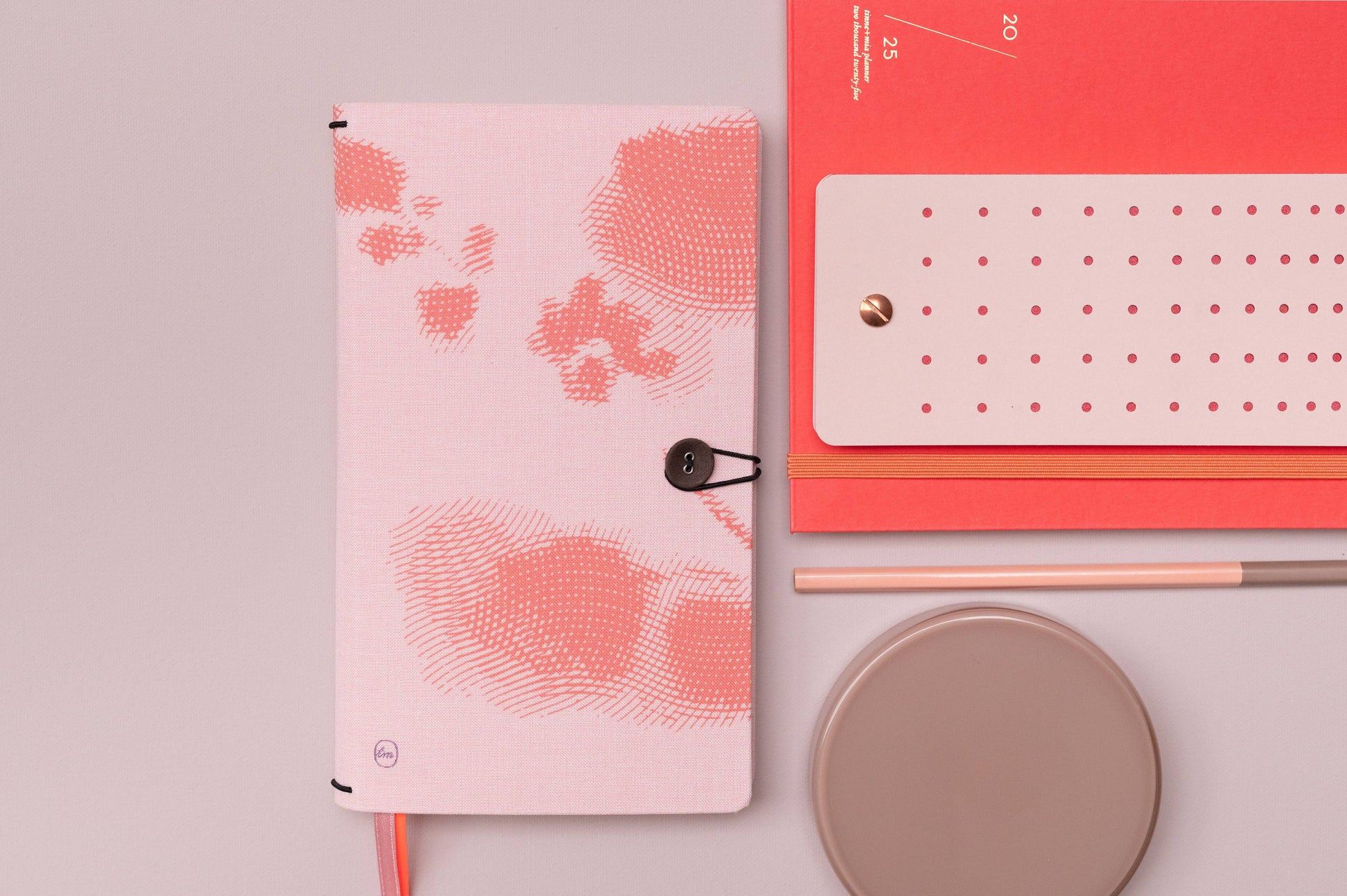 Die Tinne Mia - Aufgabenliste - Mellow Rose mit orangem, abstraktem Muster liegt neben einem coral Planner, beigem Teller und Stift auf heller Fläche. Das FSC-zertifizierte Papier steht für nachhaltige Qualität von Tinne Mia.