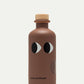 Eine braune Flasche mit einem Holzdeckel, zwei stilisierten Augen und dem Text "yiayia and friends" in der Nähe des Bodens enthält yiayia and friends - Natives Olivenöl extra mit Trüffel.