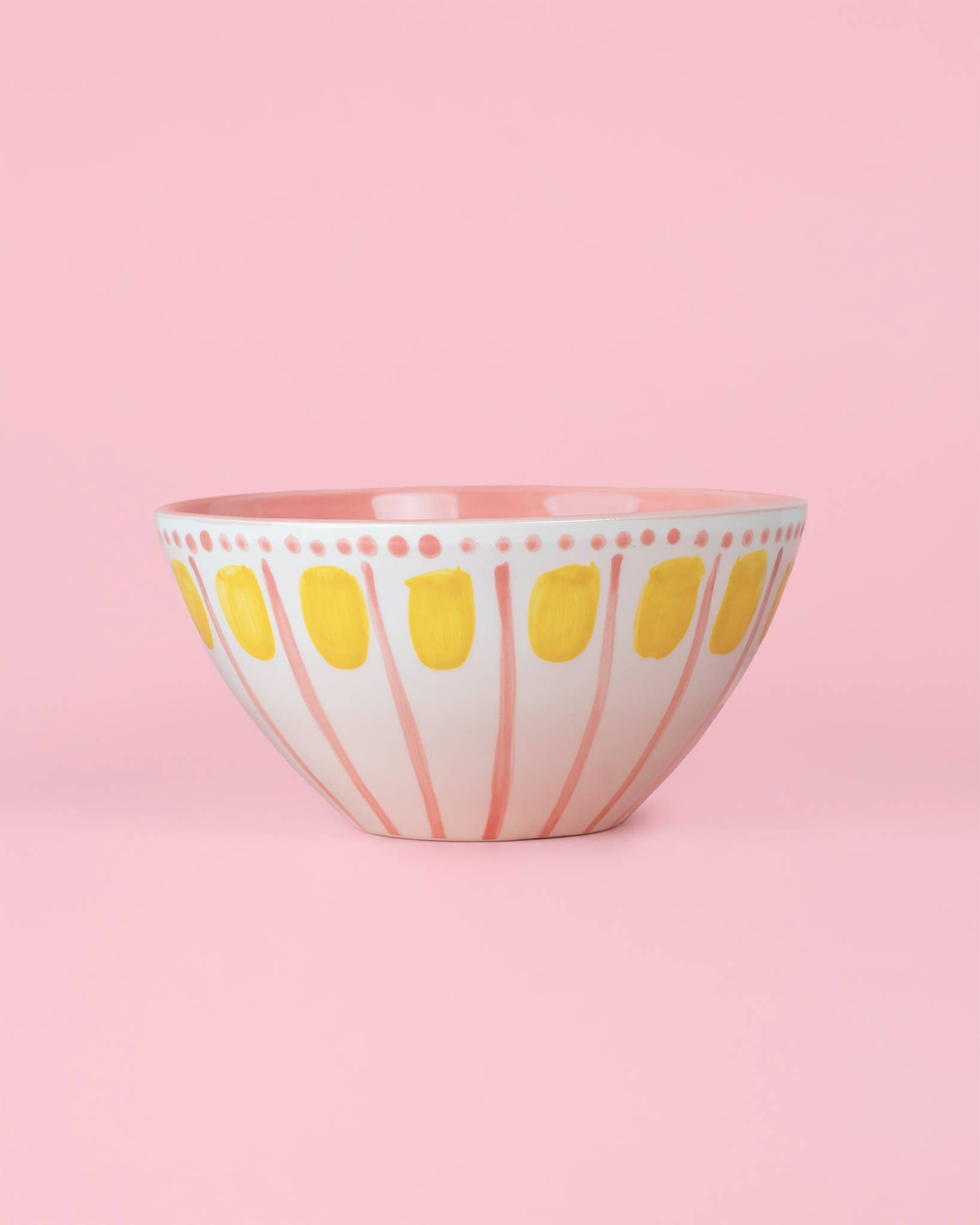 Die Alfar Tierra Cocida VALENTINA 1,5L handgefertigte Keramik-Servierschale in Rosa und Gelb besitzt eine weiße Basis mit pinken Streifen und gelben Ovalen, abgebildet vor einem rosa Hintergrund.