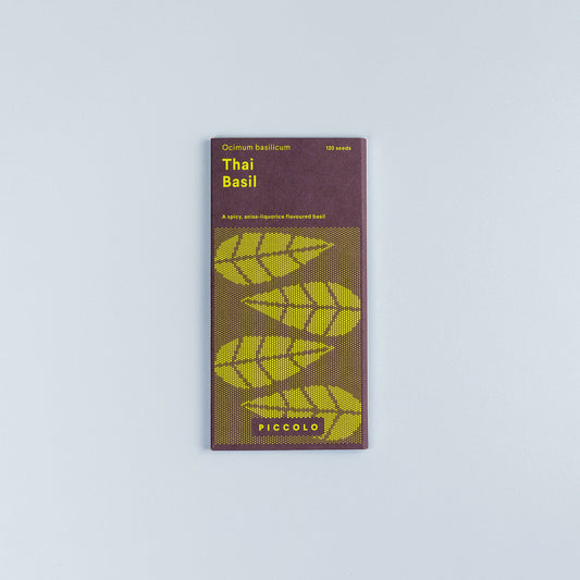 Ein Päckchen Piccolo Seeds - Basil Thai von Piccolo Seeds, mit stilisierten grünen Basilikumblättern und modernem gelben Text auf lila Hintergrund, fotografiert auf einer schlichten hellgrauen Oberfläche - ideal für Fans der asiatischen Küche.