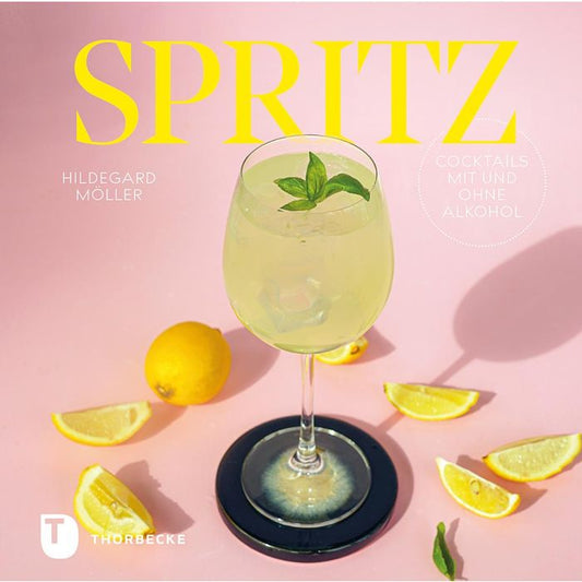Ein Glas Spritz des Thorbecke Verlags, ein hellgelber alkoholfreier Cocktail mit Eis und Minze, steht auf einem schwarzen Untersetzer inmitten von Zitronenspalten vor einem rosa Hintergrund. Der fettgedruckte gelbe Schriftzug "SPRITZ" hebt den alkoholfreien Genuss hervor.