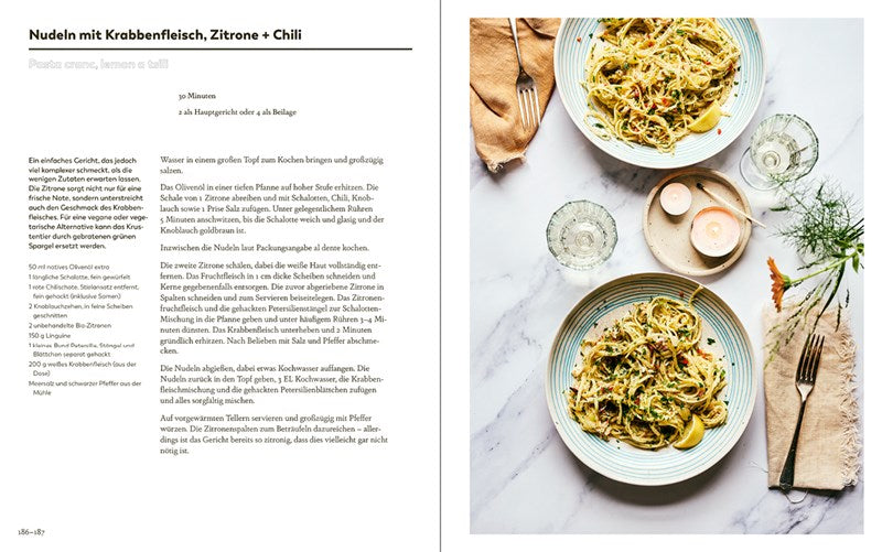 Eine Kochbuchseite aus dem Ars Vivendi Verlag "Meersalz | Meistern Sie die Kunst des perfekten Würzens" zeigt links ein Nudelrezept mit Krabben, Zitrone und Chili und rechts ein Foto von zwei schön garnierten Tellern auf einem Tisch mit Kerzenlicht.