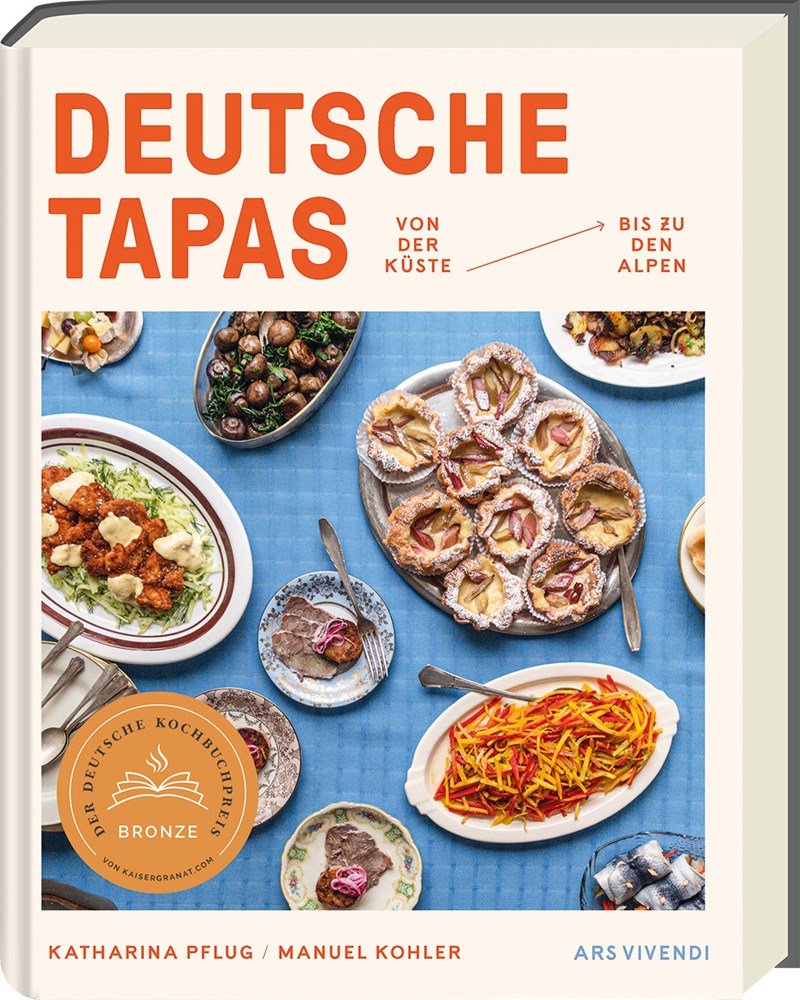 Das Cover von Deutsche Tapas aus dem Ars Vivendi Verlag zeigt deutsche Tapas auf blau-weißen Tafeln mit einem bronzenen Siegel und den Namen der Autoren - Katharina Pflug und Manuel Kohler - am unteren Rand.