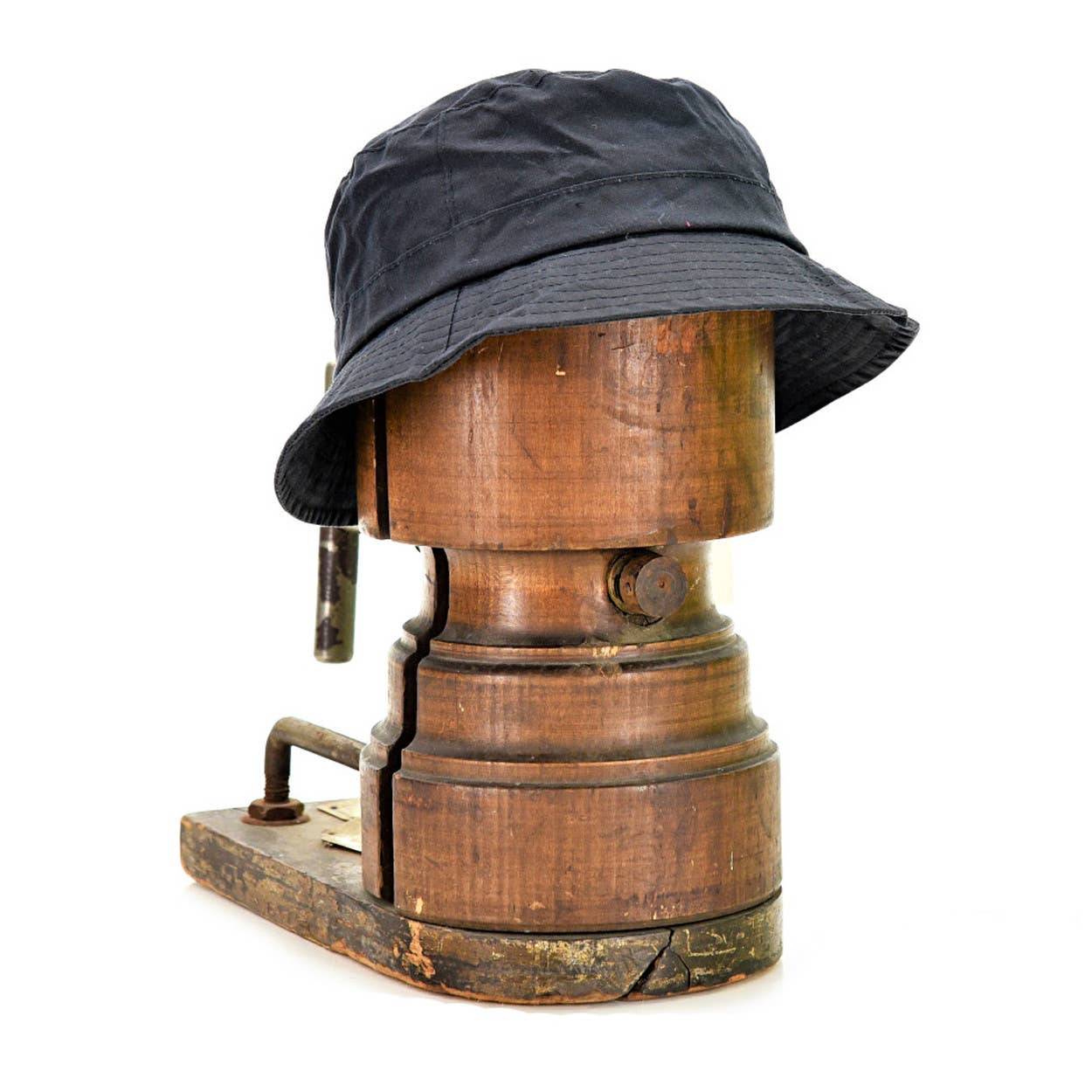 Der Tweedmill | Wachstropfen-Krempenhut von Tweedmill Textiles aus gewachster Baumwolle mit breiter Krempe ist auf einem Vintage-Holz-Hutblock vor weißem Hintergrund platziert.