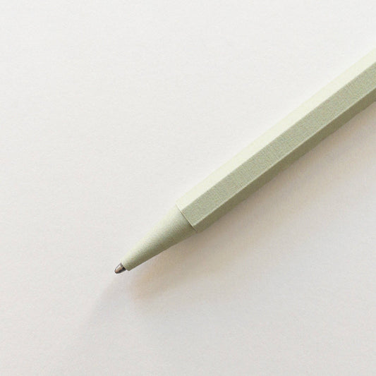 Eine Nahaufnahme des Prototo – Zero Waste Kugelschreibers in Salbei von Prototo, einem klimaneutralen, hellgrünen Stift mit sechseckigem Korpus, diagonal auf weißem Untergrund abgebildet.