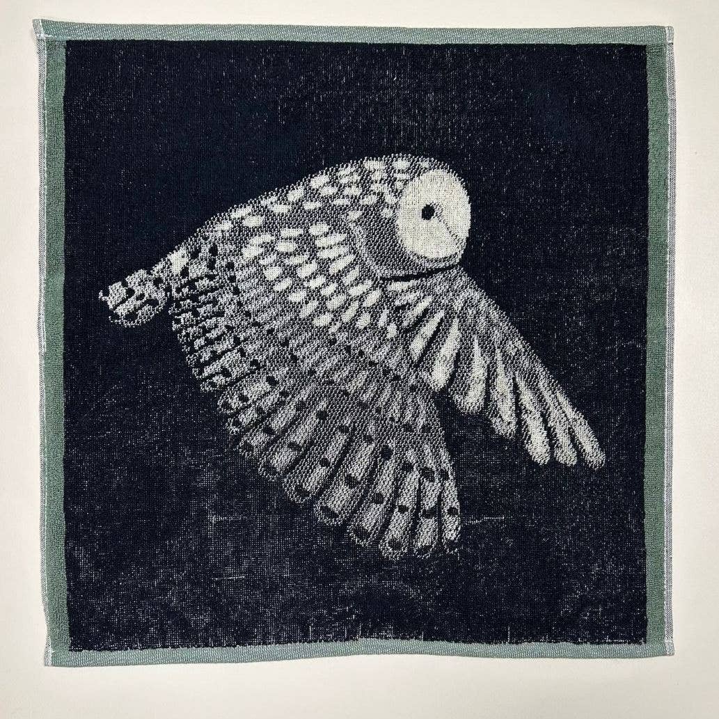 Das Küchenhandtuch "Eule" von Sylvie Thiriez zeigt eine detailreiche weiße Eule im Flug auf dunklem Grund mit filigranen Federn und hellem Rand - perfekt als OEKO-TEX zertifiziertes Küchenhandtuch.