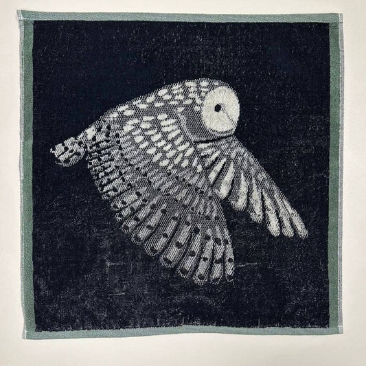 Das Küchenhandtuch "Eule" von Sylvie Thiriez zeigt eine detailreiche weiße Eule im Flug auf dunklem Grund mit filigranen Federn und hellem Rand - perfekt als OEKO-TEX zertifiziertes Küchenhandtuch.