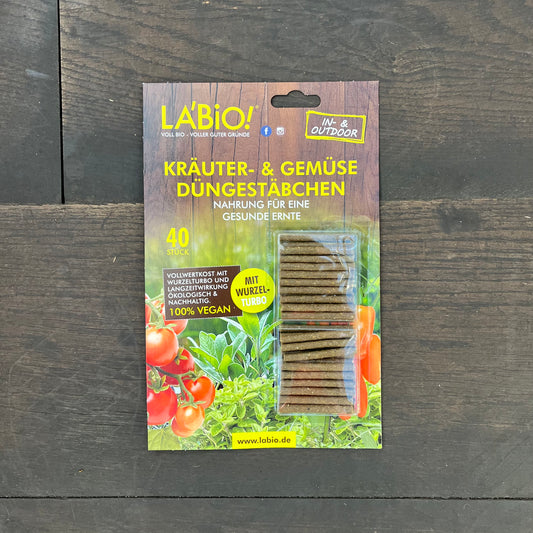 La'Bio Düngestäbchen von La'Bio: 40 nährstoffreiche Sticks in einer grünen Verpackung mit Tomaten und Pflanzen, auf Holz platziert. Ideal für Pflanzenliebhaber auf der Suche nach optimaler Nährstoffversorgung.