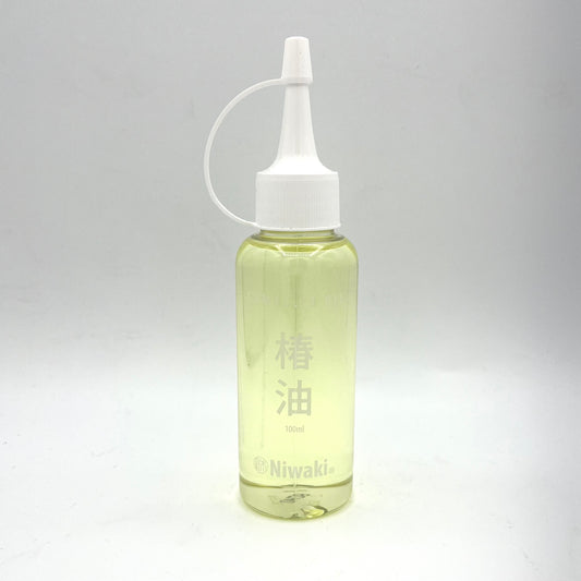 Vor einem schlichten weißen Hintergrund ist eine durchsichtige Plastikflasche mit einem weißen Düsenverschluss zu sehen, die hellgelbes Niwaki-Kamelienöl zur Klingenreinigung und zum Rostschutz enthält und auf Englisch und Japanisch mit „Niwaki“ und „100 ml“ beschriftet ist.