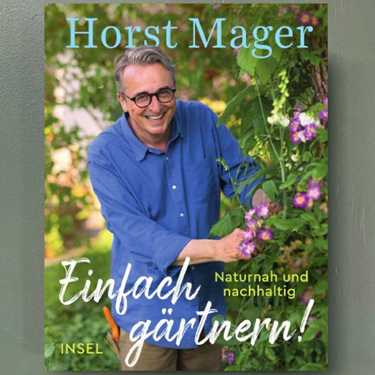 Gartenexperte Horst Mager lächelt im Garten, prüft rosa Blüten. Das Buch „Einfach gärtnern“ (signierte Ausgabe) von Horst Mager erscheint bei der Königlichen Gartenakademie.