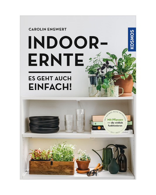 Ein Bücherregal mit Topfpflanzen, Gläsern, Geschirr, Gartengeräten und "Indoor-Ernte | Es geht auch einfach!" vom Kosmos Verlag - ideal für alle, die neugierig auf Gemüseanbau Wohnung oder die neuesten Indoor-Farming Tipps sind.