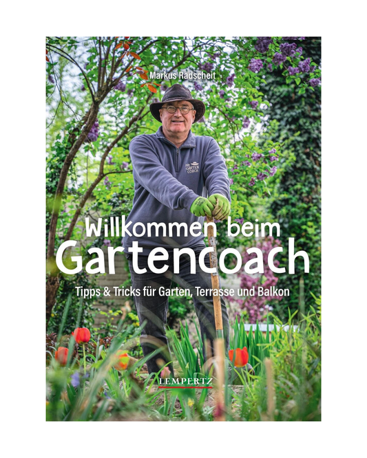 Ein Mann mit Brille und Mütze steht mit einem Spaten in einem üppigen Garten. Auf dem Bild steht der Text: Willkommen beim Gartencoach | Signierte Ausgabe von Edition Lempertz, plus deutsche Tipps zur Gartenarbeit.