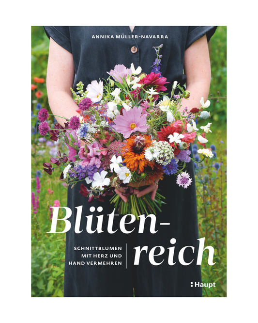 Eine Person in einem dunklen Kleid hält einen farbenfrohen Strauß aus nachhaltig angebauten Blumen. Unscharfes grünes Laub ist im Hintergrund zu sehen. Das Cover zeigt das Buch "Blütenreich | Schnittblumen mit Herz und Hand vermehren" aus dem Haupt Verlag.