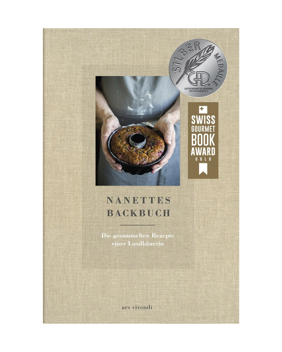Eine Person hält einen runden Laib in einer Backform. Das Cover von "Nanettes Backbuch | Backen wie bei Oma" vom Ars Vivendi Verlag zeigt eine Silbermedaille und den Swiss Gourmet Book Award Gold für traditionelle Rezepte.
