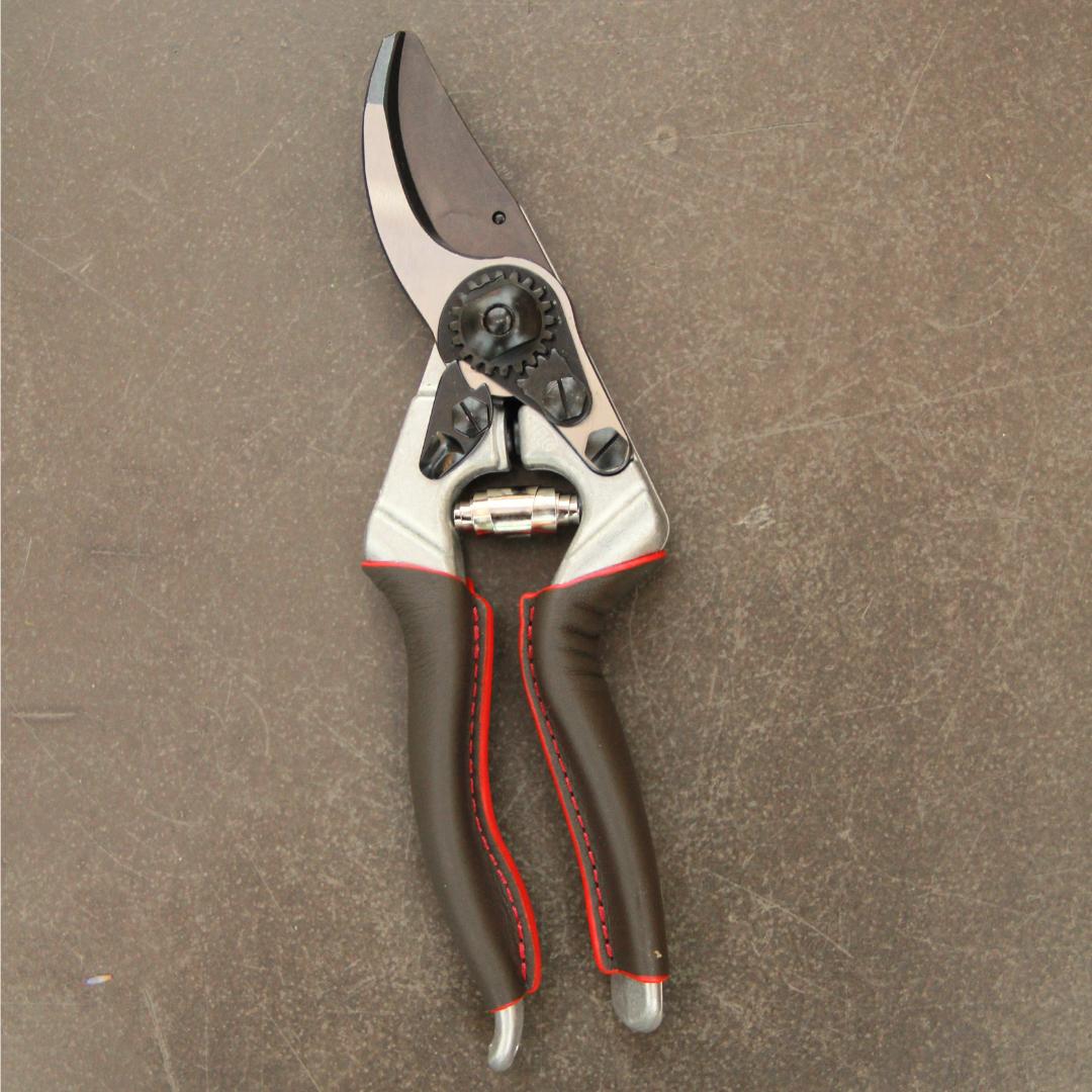 Ein Paar Felco 8 ELITE Gartenscheren von Felco mit braunen ergonomischen Griffen und einer silbernen Klinge ruht auf einer strukturierten braunen Oberfläche.