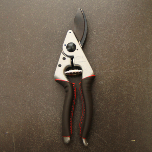 Ein Paar Felco 8 ELITE Gartenscheren von Felco mit schwarzen Klingen und Griffen mit roten Nähten ruht auf einer dunklen, strukturierten Oberfläche.