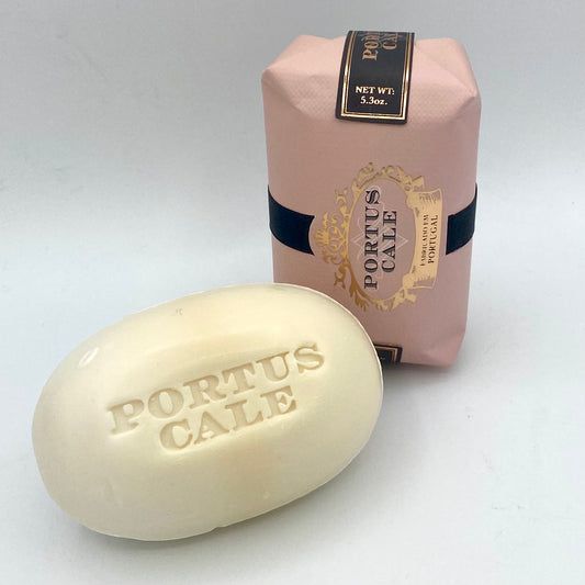 Ein Castelbel Seife Portus Cale Rosé Blush 150 g Riegel mit der Prägung PORTUS CALE steht vor seiner rosafarbenen, eleganten Verpackung auf weißem Hintergrund und erinnert an die Anmut der Lotusblume.