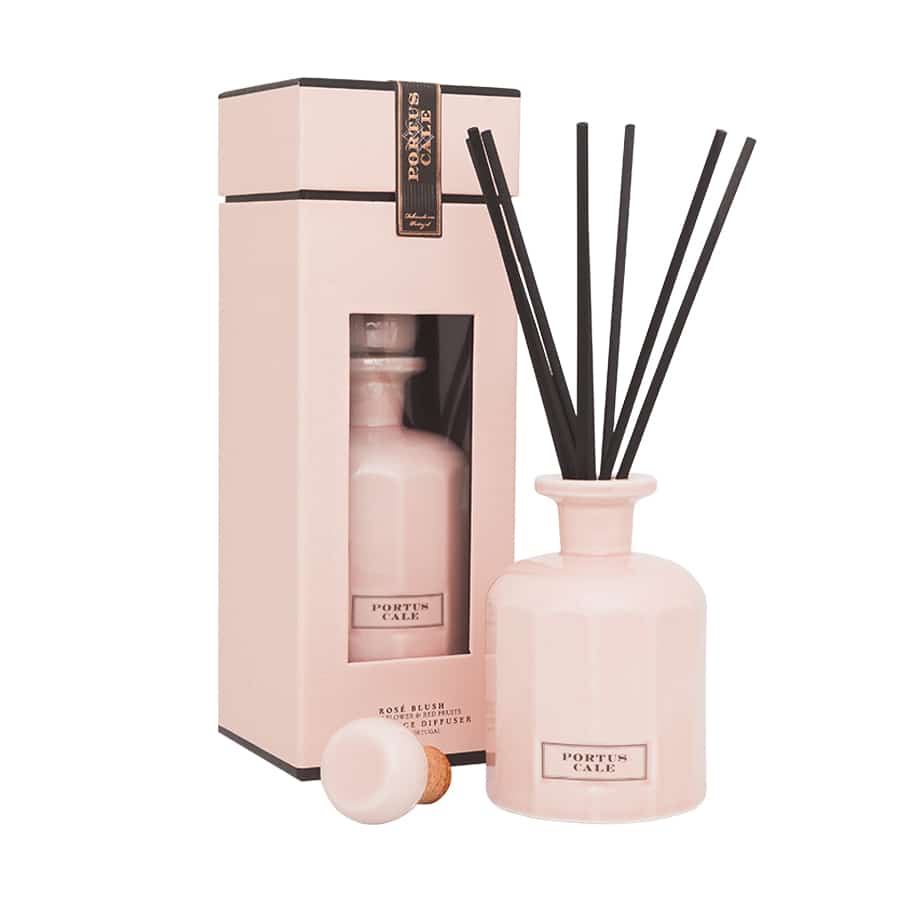 Ein blassrosa Castelbel Diffusor | Rosé Blush 250 ml mit schwarzen Stäbchen steht neben der passenden Schachtel. Auf dem Etikett steht "Rosé Blush", und der Korken der Flasche ist davor platziert.