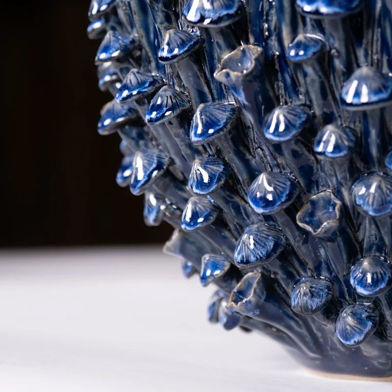 Eine Nahaufnahme zeigt die Vase | Blau skulptural L von Des Pots: Handgefertigtes Steinzeug mit glänzenden dunkelblauen pilzartigen Formen, dicht angeordnet auf glatter, heller Oberfläche.