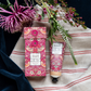 Das William Morris at Home 'Strawberry Thief' Handcreme 50 ml Set wird in einer passenden Geschenkbox geliefert. Es ist auf gestreiftem Tuch mit dunkelblauem Samt abgebildet und wird von lila und weißen Blumen akzentuiert.
