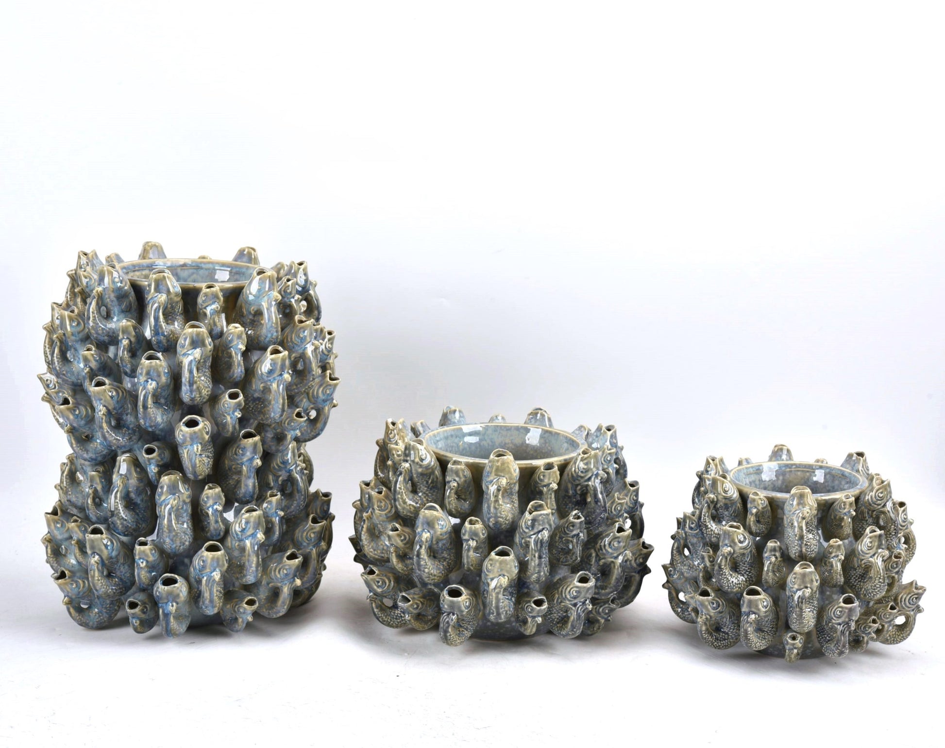 Die Vase von Des Pots aus Steingut, Modell 'Fisch' Groß in Blau, besticht durch ihre handgeformte Form und zahlreiche röhrenförmige Ausstülpungen. Sie ist vor weißem Hintergrund arrangiert.