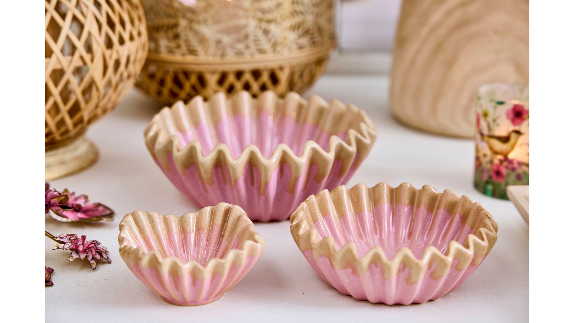 Drei kleine rosa Schalen 'Wave' von 2 Have (5 x 10 cm) stehen auf einer weißen Oberfläche. Im Hintergrund sind dekorative Körbe und getrocknete Blumen arrangiert.