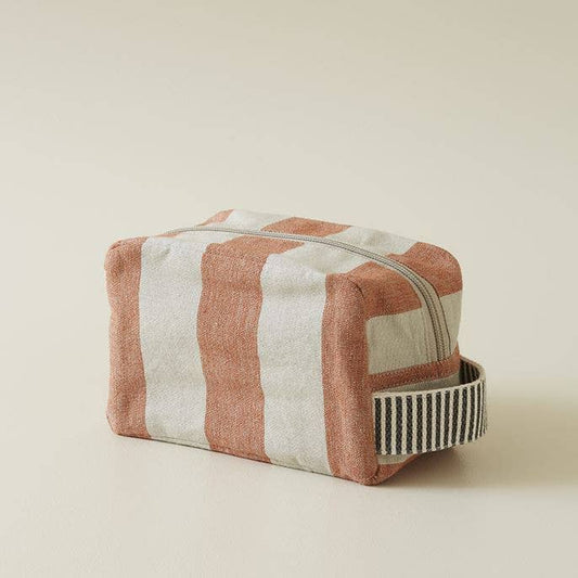 Der Sylvie Thiriez Kulturtbeutel Mistral ziegelrot klein ist ein rechteckiger Beutel mit auffälligen orangefarbenen und gebrochen weißen Streifen, einem Reißverschluss an der Oberseite, einem schwarz-weiß gestreiften Griff und ist nach OEKO-TEX® STANDARD 100 zertifiziert.