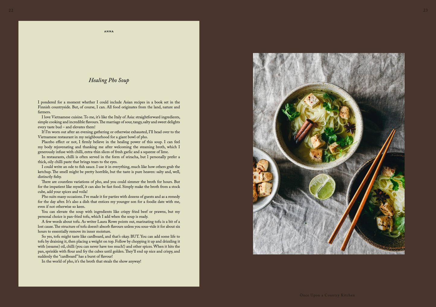 Eine Schüssel Pho mit Tofu, Nudeln, Pilzen und Kräutern steht neben Essstäbchen und einer Serviette und verströmt rustikalen Charme – eine Szene, die von „Once Upon a Country Kitchen“ von Cozy Publishing inspiriert ist.