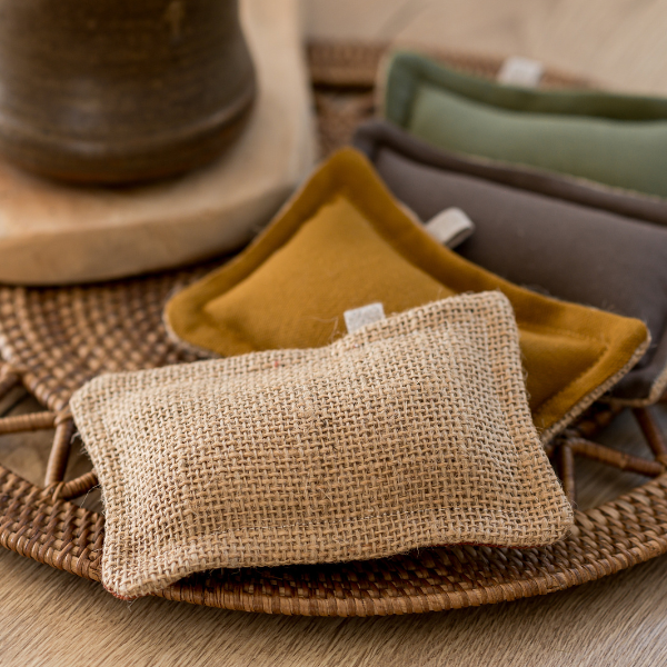 Drei einfache Dinge – Waschbarer Schwamm | Die Scharfen, handgefertigt aus Baumwolle/Jute in Beige, Senfgelb und Olivgrün, liegen auf einem Tablett neben einer Keramiktasse auf Holz. Marke: Simple Things.