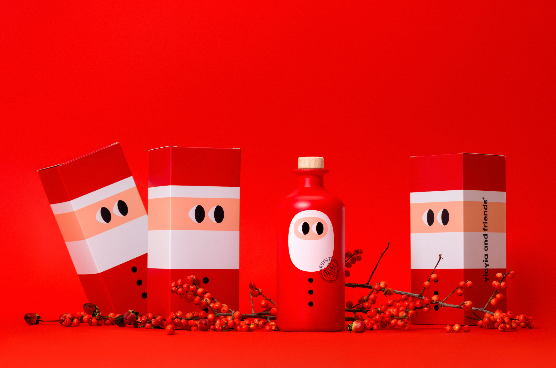 Festliche rote Flasche und drei Schachteln mit minimalistischen Weihnachtsmannmotiven auf leuchtend rotem Hintergrund. yiayia and friends - Natives Olivenöl extra - Weihnachtsedition 500 ml-das perfekte Geschenk für Feinschmecker, umgeben von roten Beeren und Zweigen.