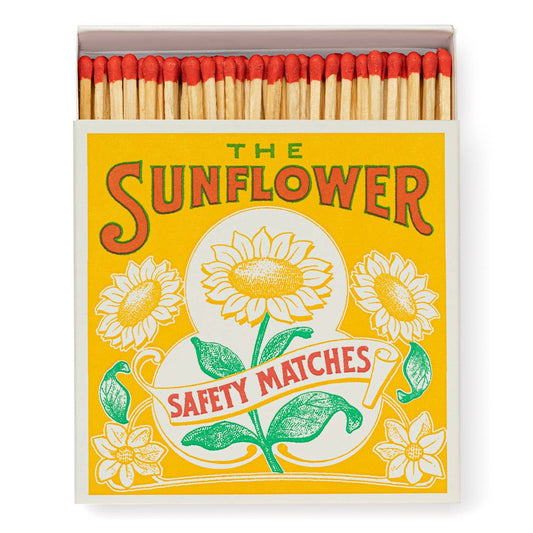 Die Archivist Gallery - Sunflower | Square - Sicherheitsstreichhölzer von Archivist Gallery hat eine leuchtend gelbe und weiße Schachtel mit floralen Abbildungen von Sonnenblumen und grünen Blättern; die Streichhölzer im Inneren haben rote Spitzen.